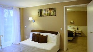 A hotel room with a bed, a painting of a forest, and a door leading to another room. - Waldhotel Wilhelmshöhe (Freudenberg)