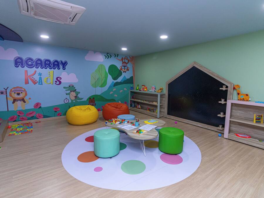 Un cuarto de juegos infantil con un mural, pufs, una mesita y estanterías llenas de juguetes.