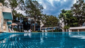 A swimming pool with lounge chairs and a pergola, surrounded by trees and buildings. - Hotel Casino Acaray (Ciudad Del Este)