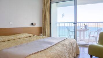 Ein Hotelzimmer mit Bett, einem Balkon mit Tisch und Stühlen sowie Meerblick.