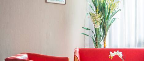 Quarto moderno com sofá vermelho, poltrona vermelha e mesa de centro de vidro.