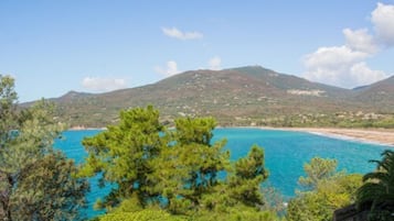 A coastal landscape with a clear view of the sea and a mountain in the background.