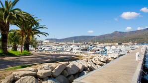A marina with boats docked, a wooden walkway, and palm trees. - Hôtel Roc e Mare (Propriano)