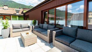Un espace extérieur moderne, aménagé avec des meubles en osier et de grandes fenêtres.