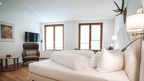 Une chambre d’hôtel moderne avec un grand lit, une chaise, une petite table et un téléviseur.