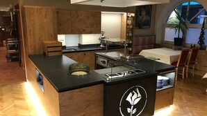 Une cuisine moderne avec des meubles en bois, un îlot central doté d’une vitrine, et un coin repas avec une table et des chaises.
