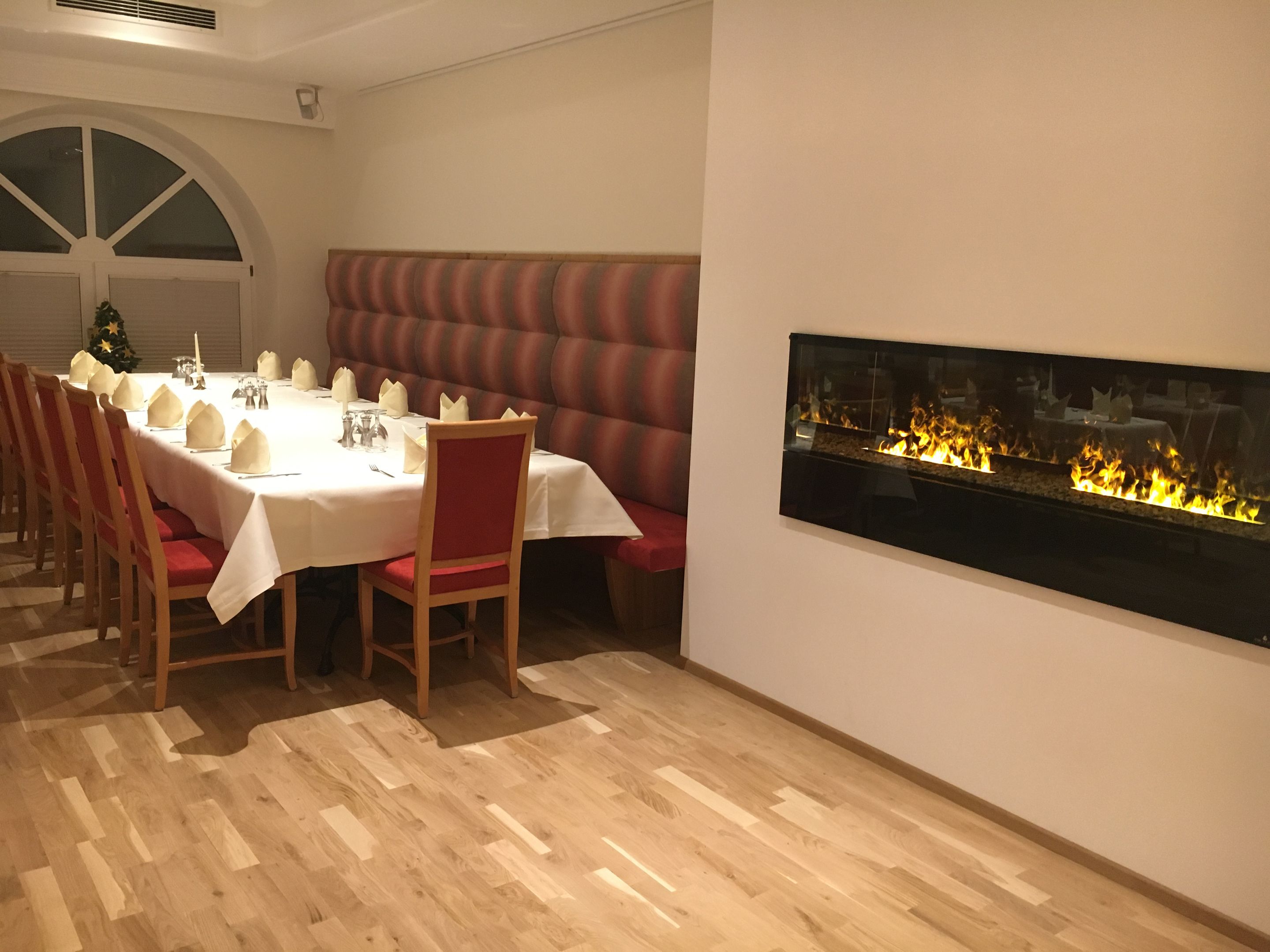 Un comedor con una larga mesa lista para una comida, una chimenea y un árbol de Navidad.