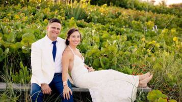 A couple seated on a bench surrounded by lush greenery.