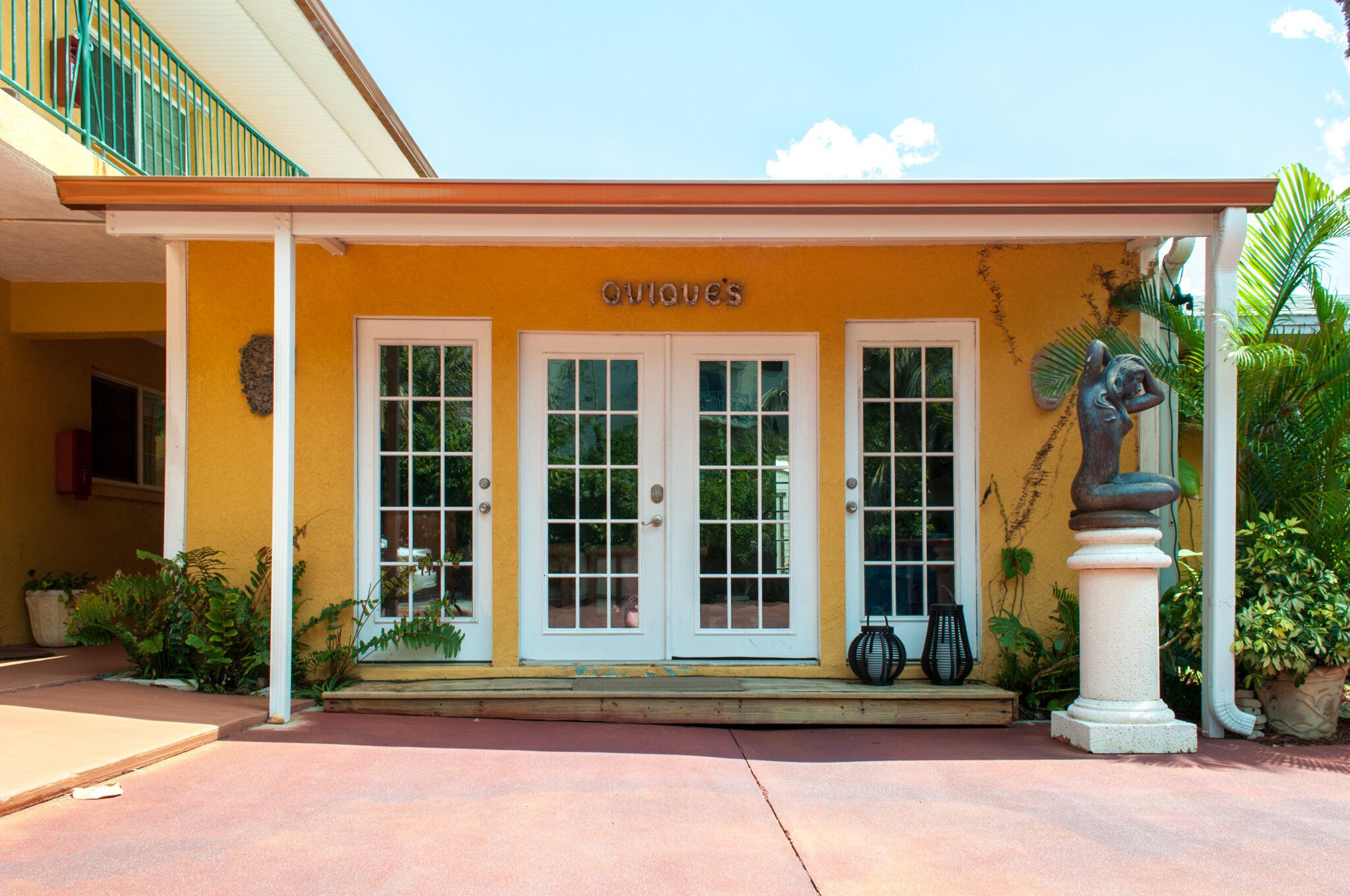 A building with a yellow facade, white doors, and a sign reading "OVIQUES".