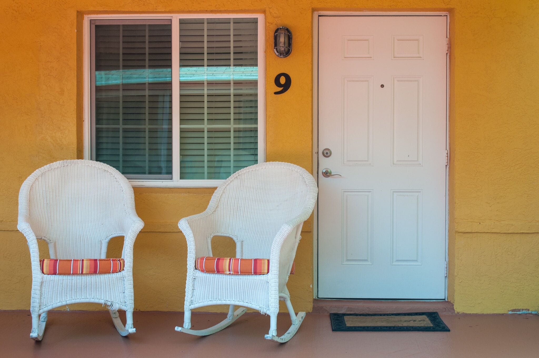 Two rocking chairs in front of a white door with the number 9 on the wall.