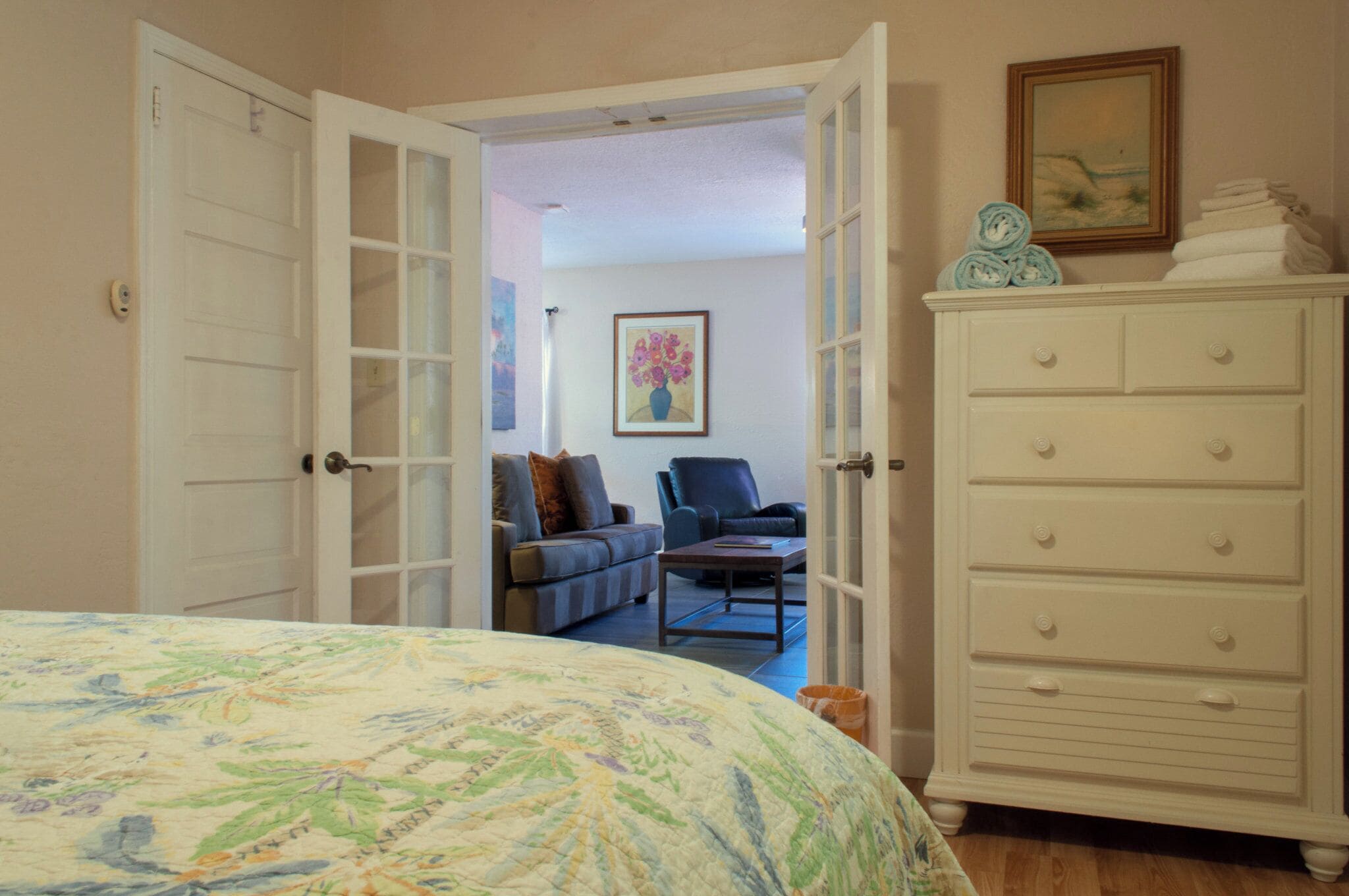Una puerta abierta que da a una sala de estar con un sofá, un sillón y un cuadro en la pared.