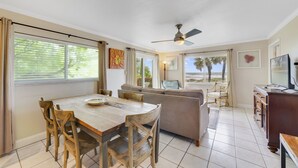 A dining area with a wooden table and chairs, a sofa, and a television.