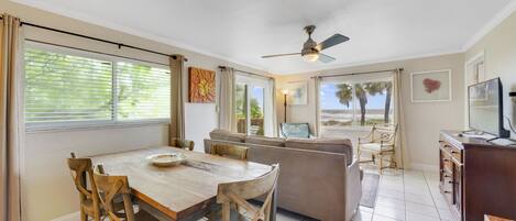 A dining area with a wooden table and chairs, a sofa, and a television.