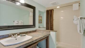 A bathroom with a sink, mirror, shower, and towel rack.