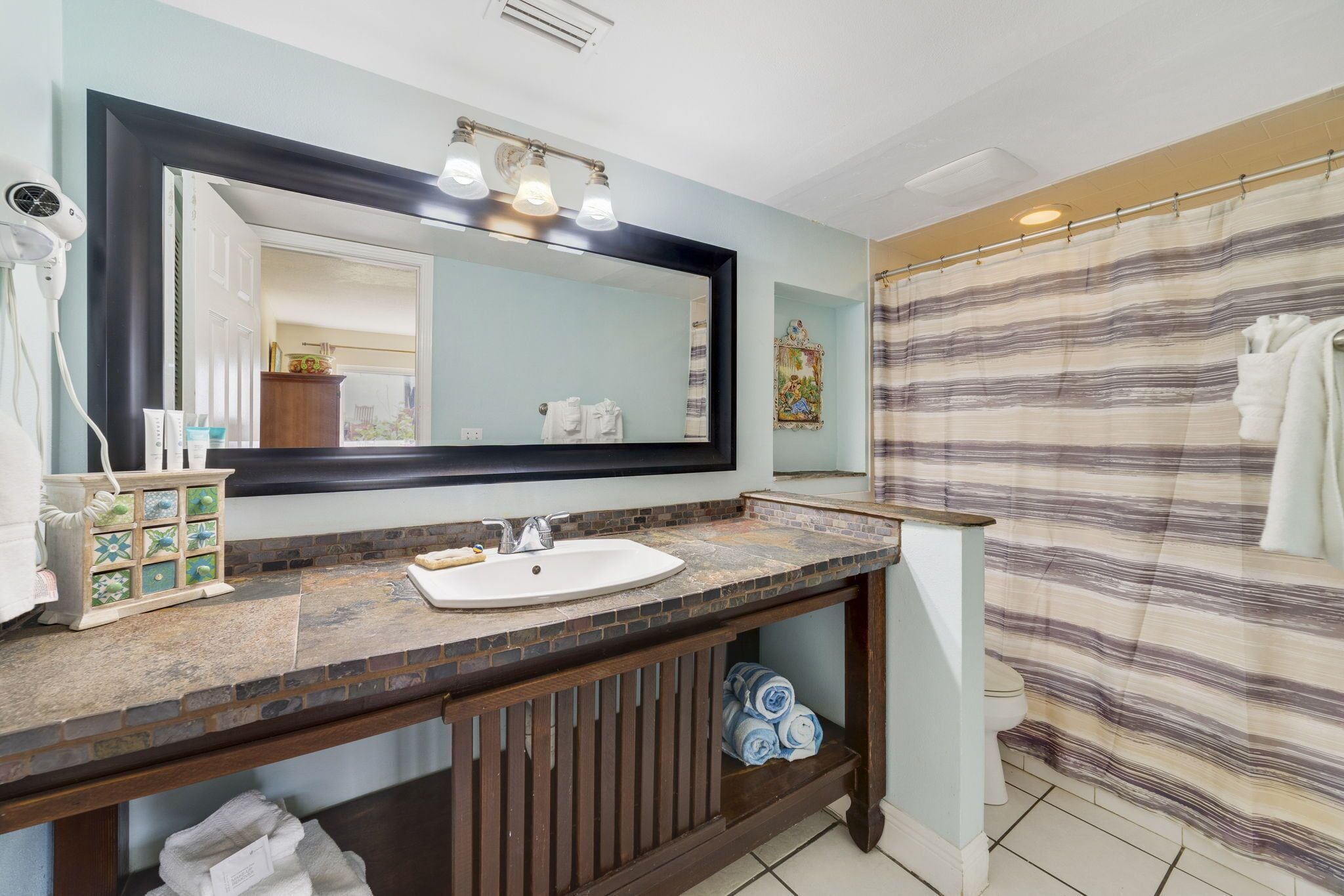 A bathroom with a large mirror, a sink, and a shower curtain.