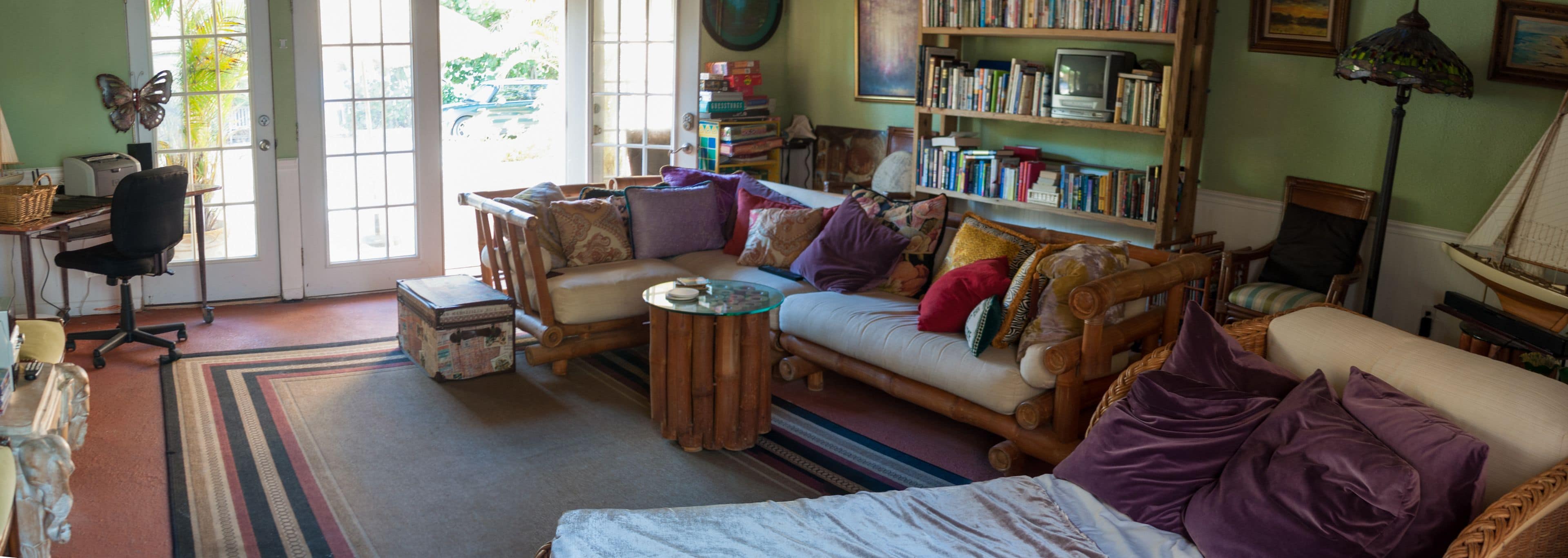 A cozy living room with a sofa, armchairs, a coffee table, and a bookshelf filled with books.