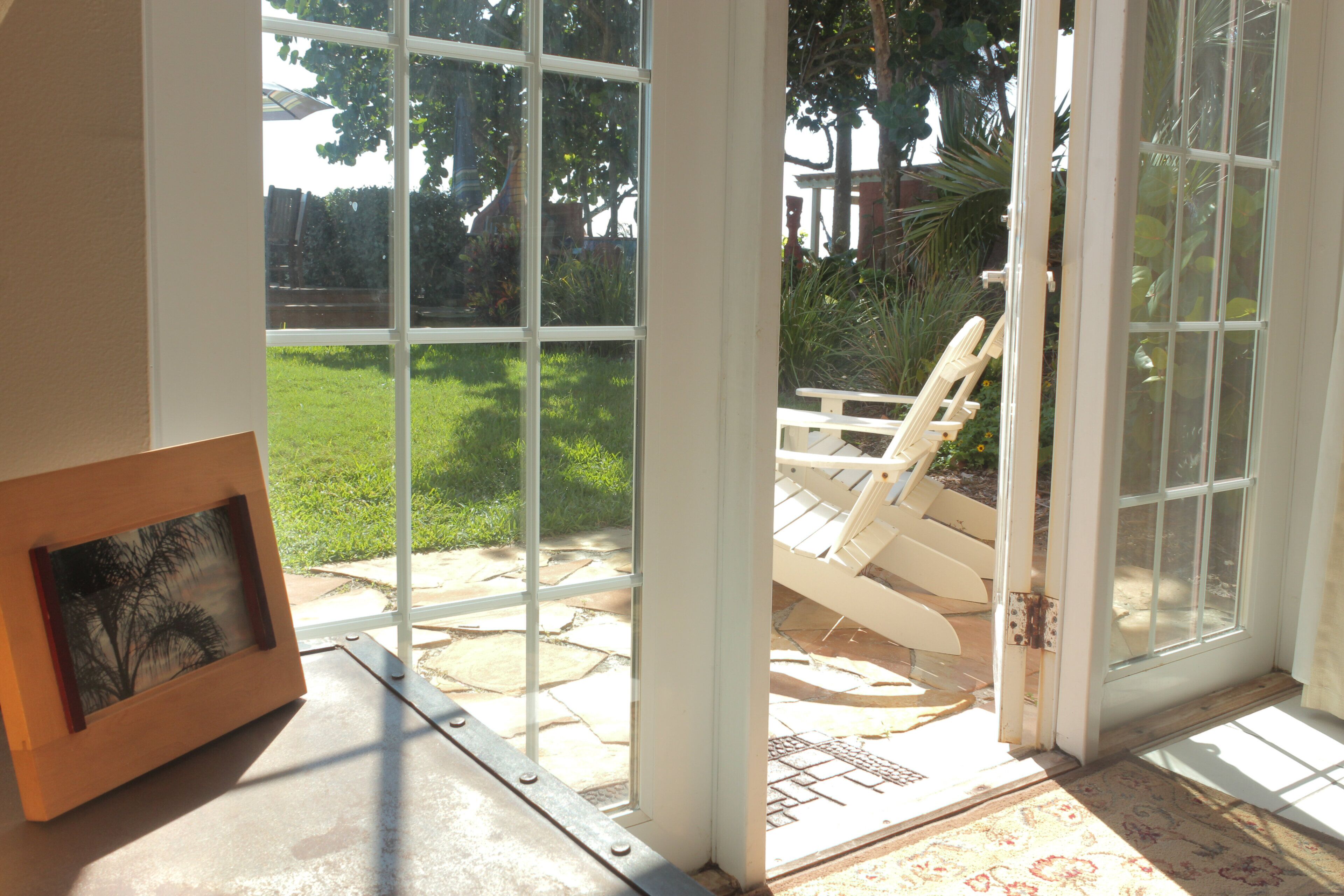 Une pièce dotée d’une grande porte vitrée donnant sur un patio extérieur avec un sol en pierre et une chaise en bois.