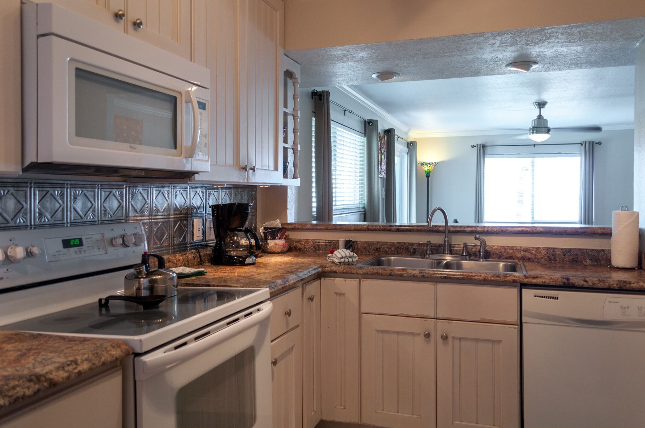 A kitchen with white cabinets, a microwave, stove, and dishwasher.