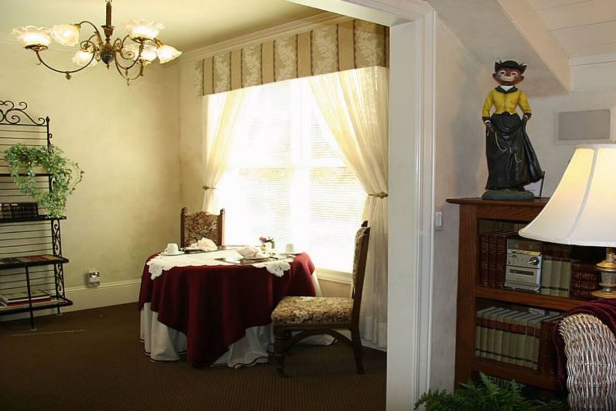 Ein gemütliches Zimmer mit Esstisch, Bücherregal, Lampe und einer Zierfigur.