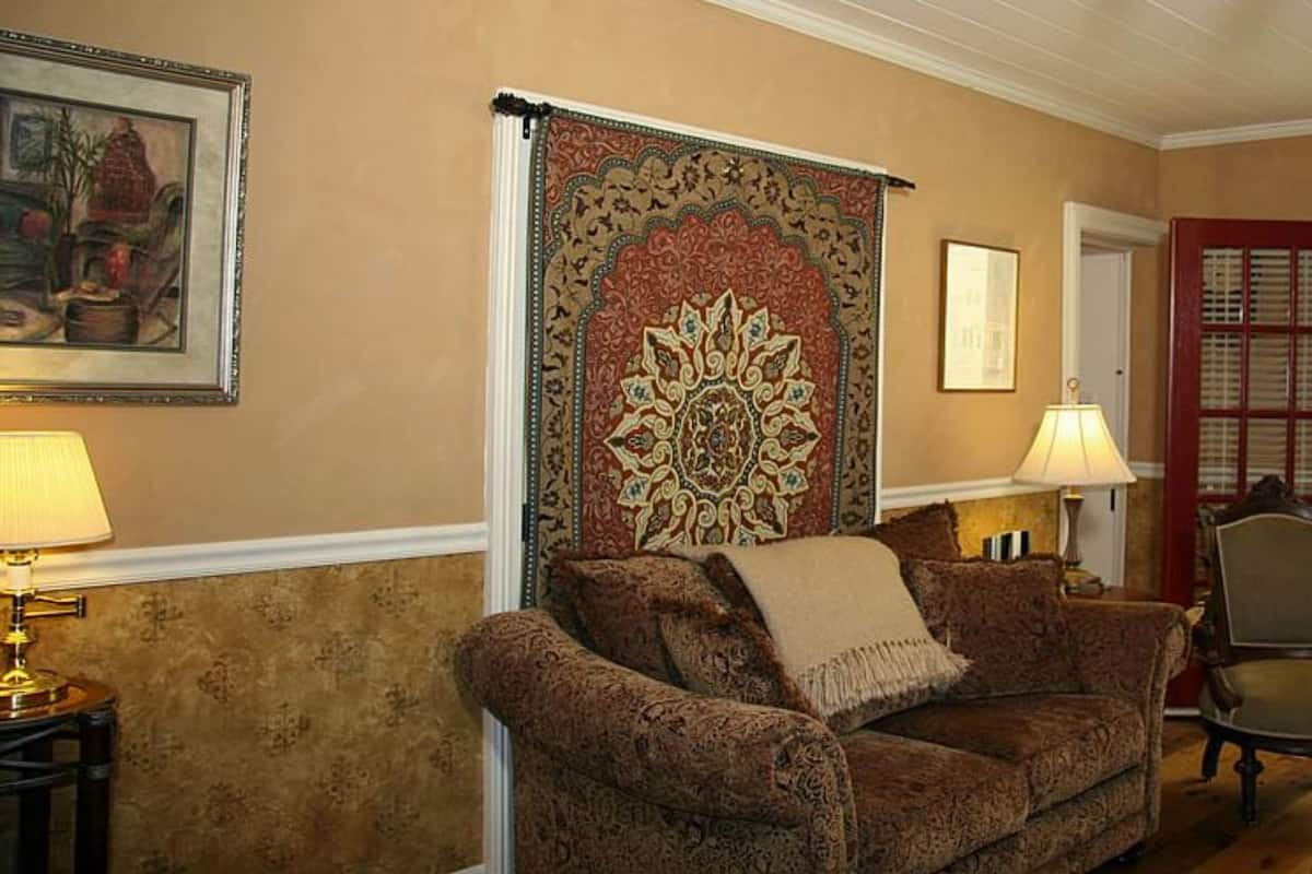 Ein gemütliches Wohnzimmer mit Teppichmuster, einem braunen Sofa, einem Sessel und einer Tür, die auf einen Balkon führt.