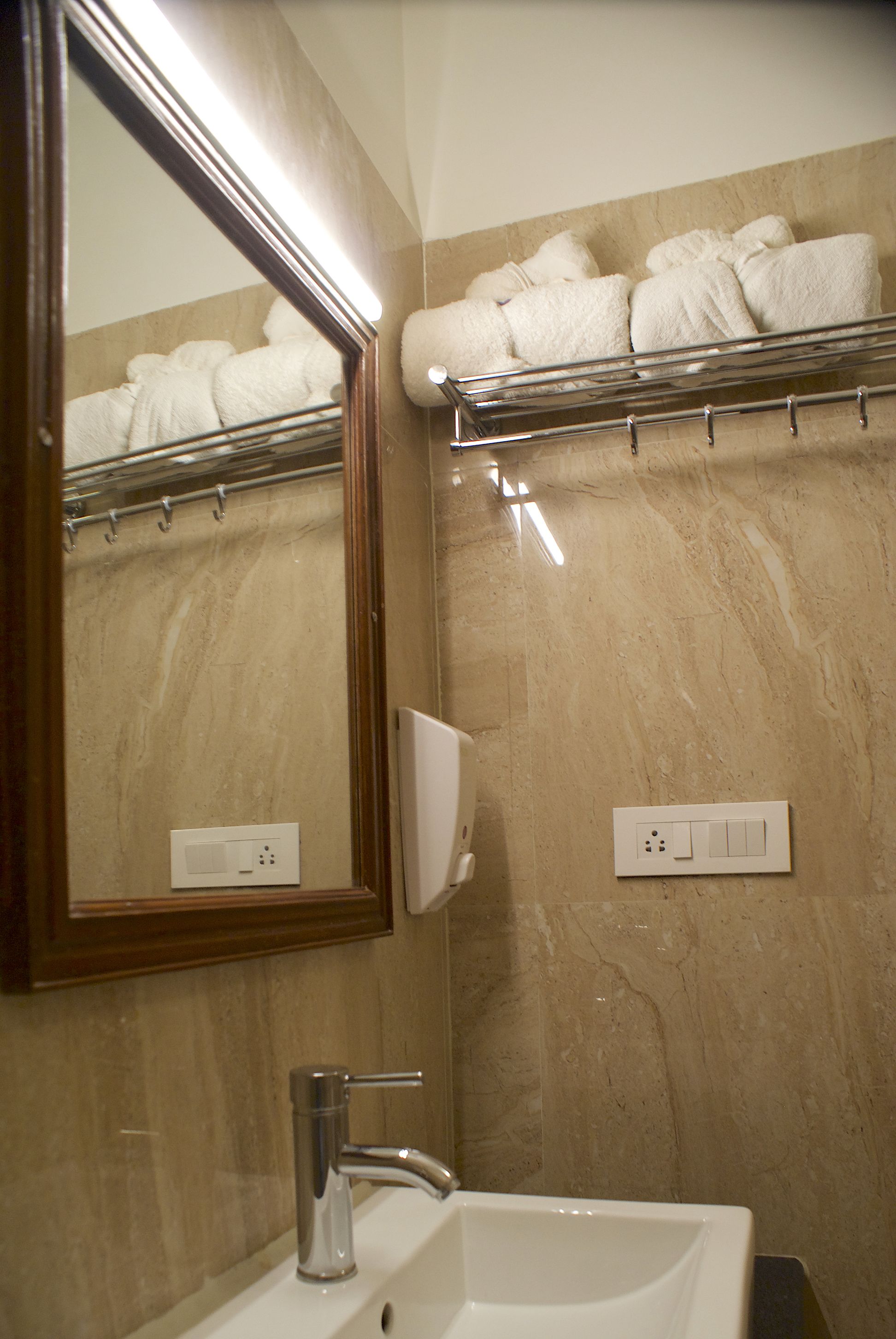 Un baño con lavabo, espejo, toallero y paredes de mármol.