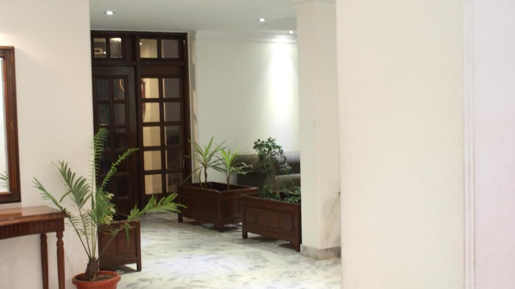 A hallway with a wooden door, potted plants, and a sofa.
