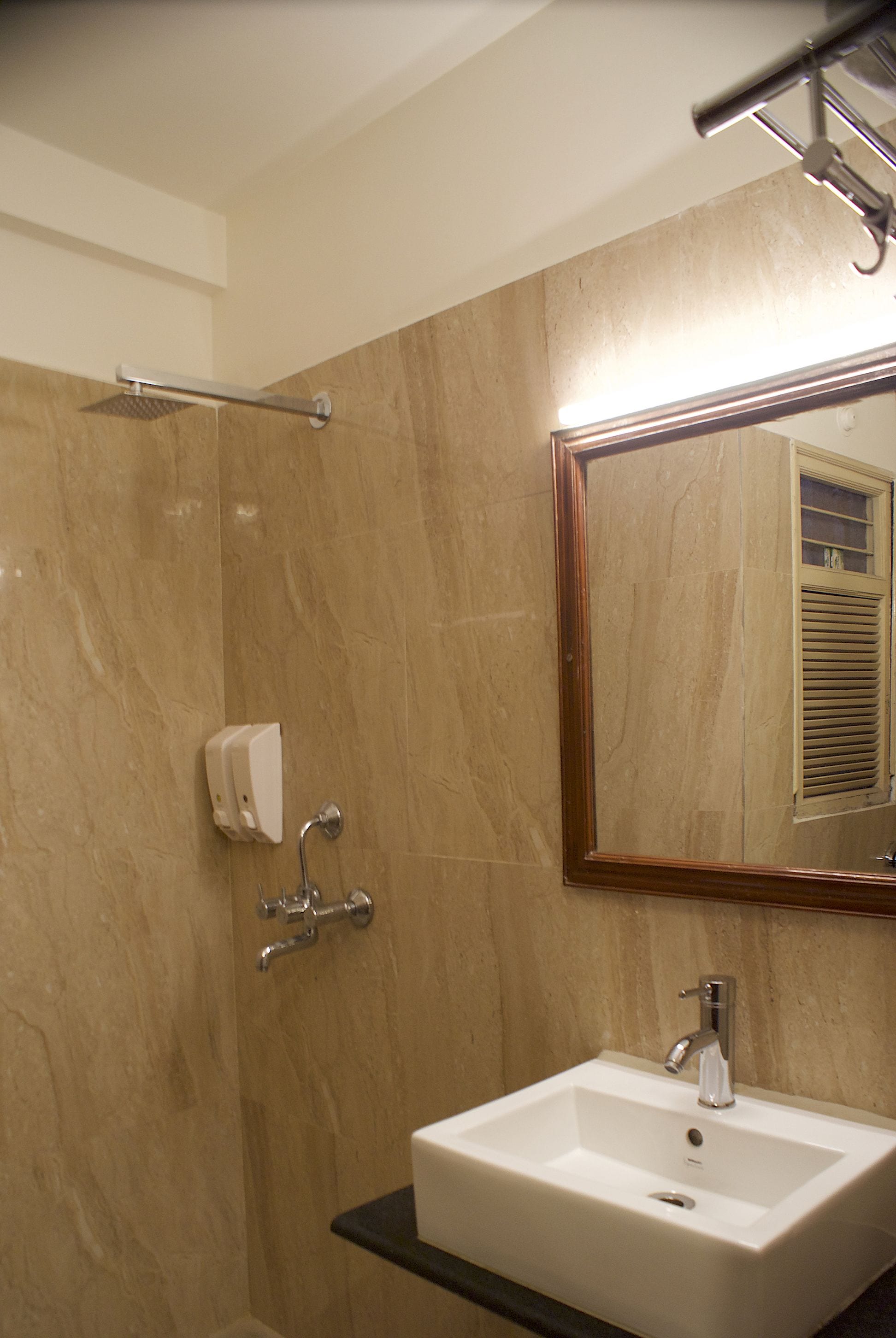 A bathroom with a white sink, a mirror, and a shower area.