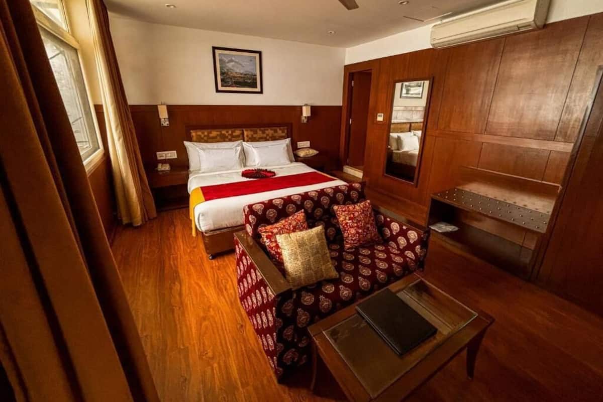 A hotel room with a bed, a sofa, a small table, and a wooden cabinet.