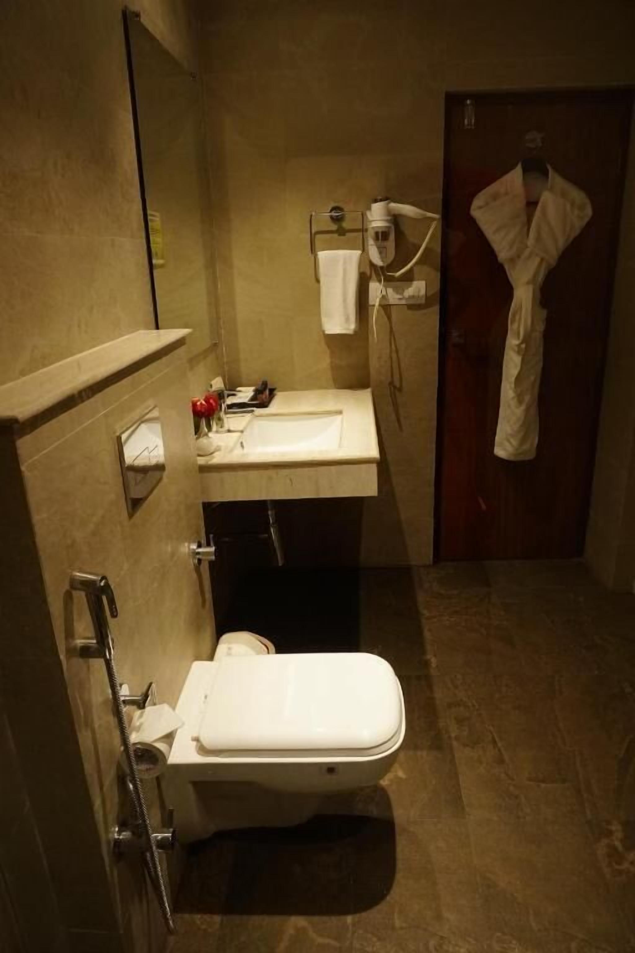 Un bany amb vàter, un lavabo i una bata penjada a la porta.