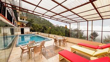 Una piscina al aire libre, sombrillas, sillones reclinables de piscina