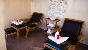 Relax in a serene spa room with a wooden shelf unit, three comfortable chairs, and a decorative panel.