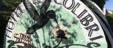 A mosaic sign with a bird design and the words "Hotel El Colibri SPA".