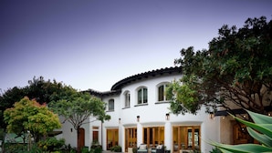 A white building with multiple windows and doors, surrounded by trees and plants. - El Colibri Hotel & Spa (Cambria)
