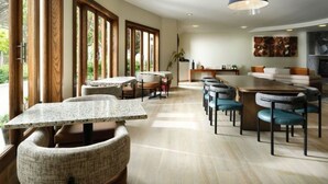 A spacious dining area with multiple tables and chairs, large windows, and a modern ceiling light. - El Colibri Hotel & Spa (Cambria)