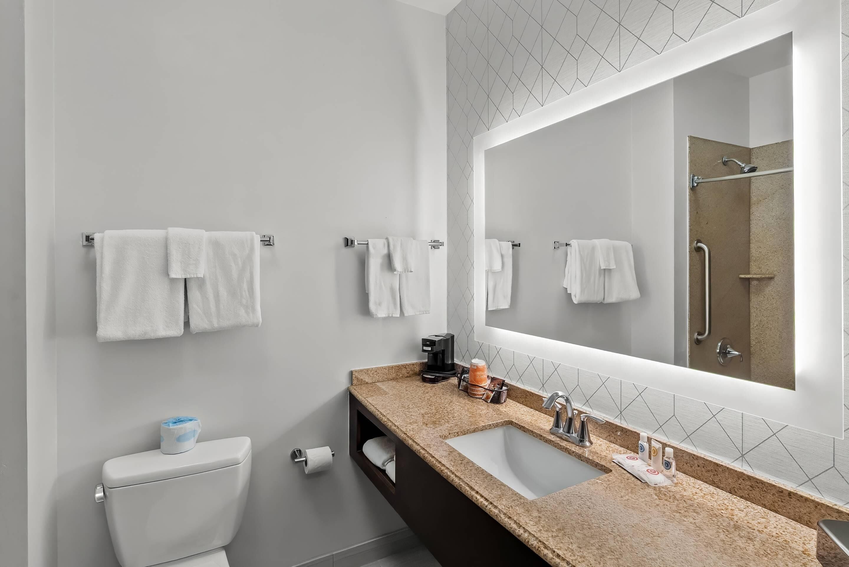 A modern bathroom with a toilet, sink, and large mirror.