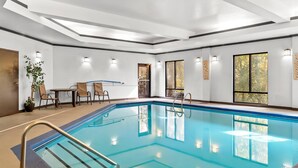 An indoor swimming pool with clear blue water, surrounded by a modern interior with white walls, recessed lighting, and large windows. - Comfort Suites Simpsonville - Greenville (Simpsonville)