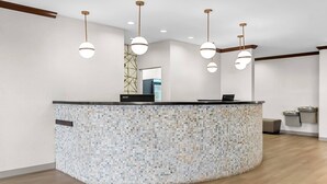 A reception area with a mosaic-tiled counter, multiple pendant lights, and a laptop on the counter.