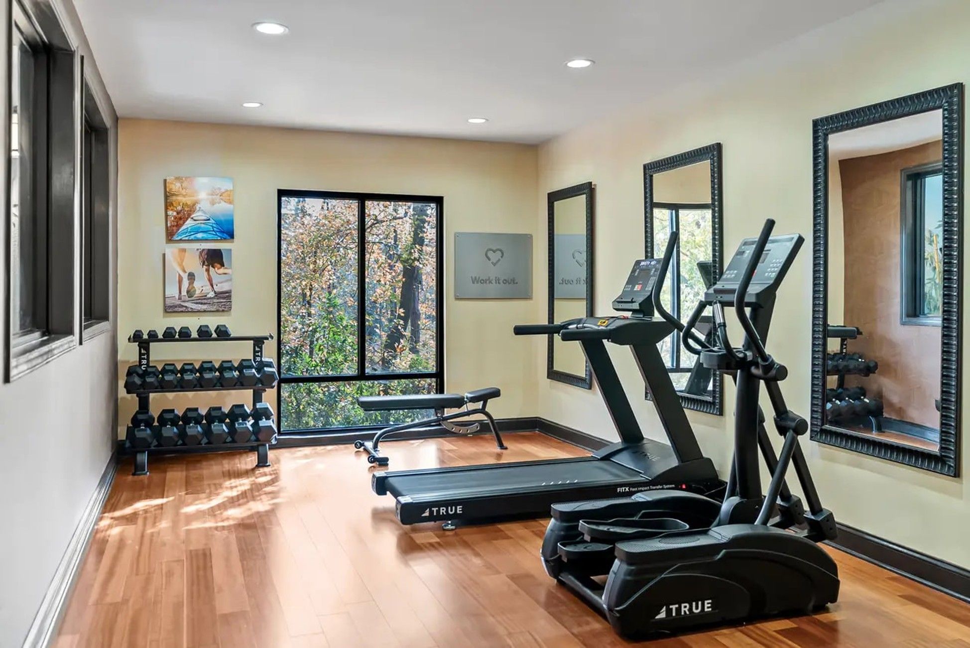 A gym with treadmills, elliptical machines, and dumbbells.