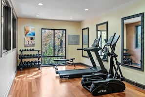 A gym with treadmills, elliptical machines, and dumbbells.