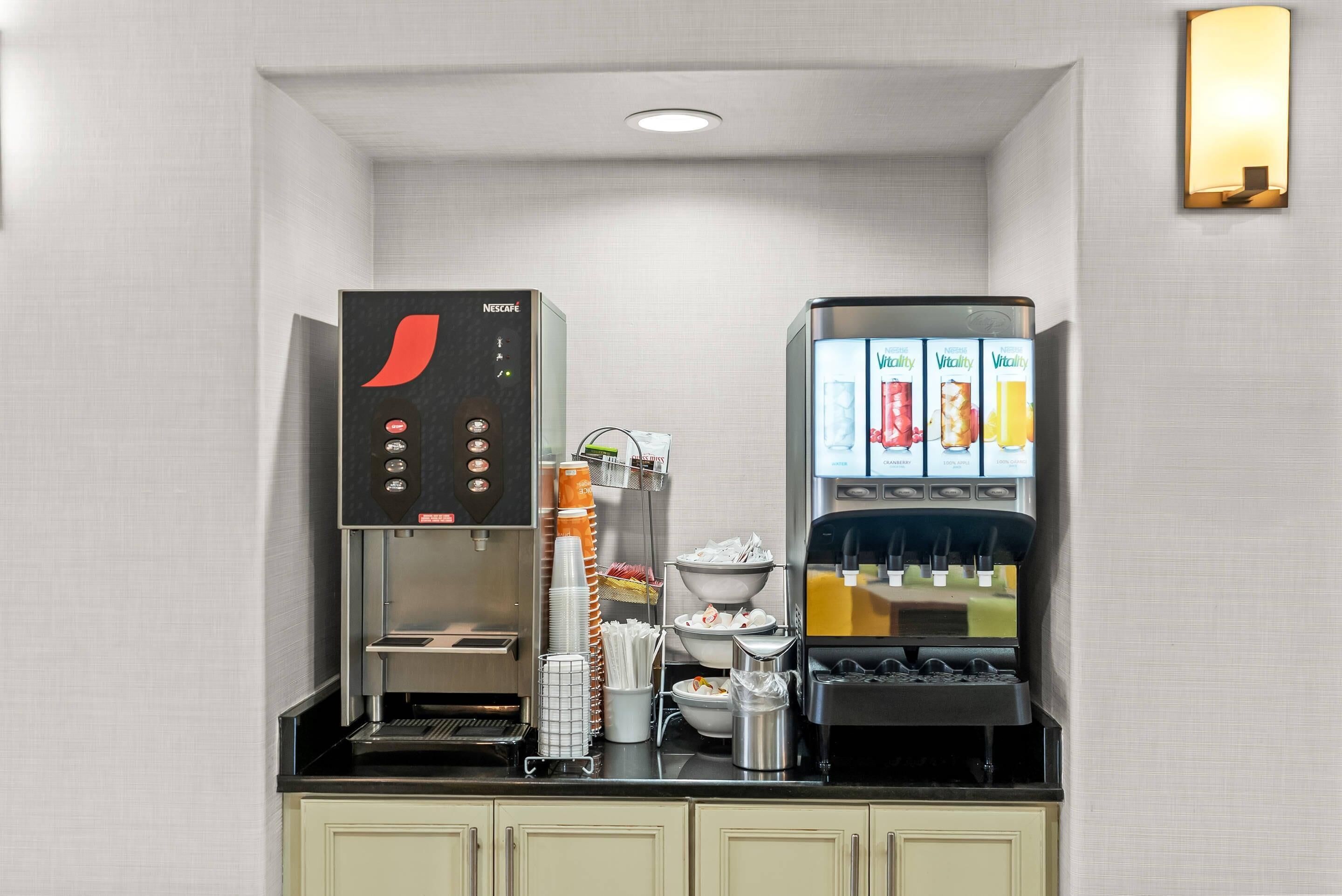 A compact coffee station with a coffee machine, a beverage dispenser, and a menu display.