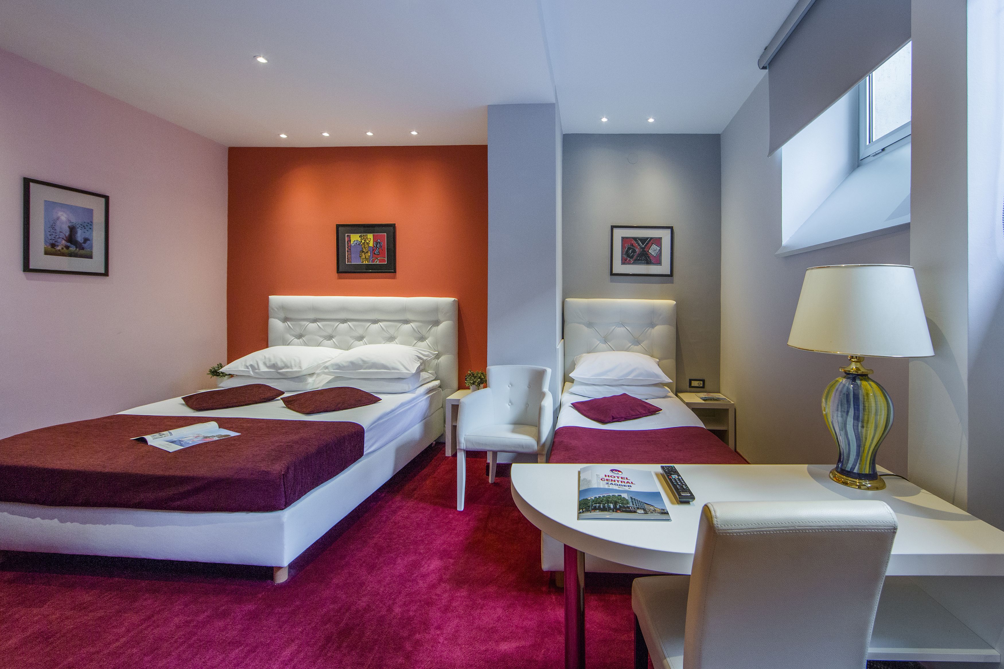 Una habitación de hotel con dos camas, un escritorio, una silla y una lámpara.