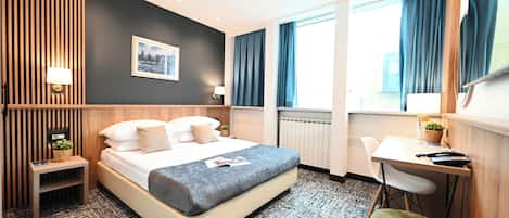 A modern hotel room with a large bed, bedside tables, a desk, and a chair.