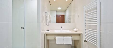 Un baño moderno con cabina de ducha de vidrio, lavamanos con toallero y radiador blanco.