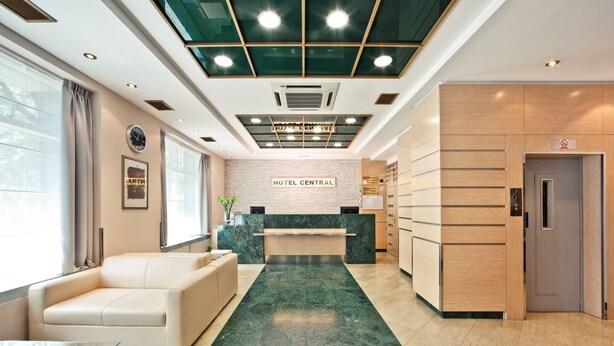 A hotel lobby with a reception desk, a waiting area with a sofa, and a green marble floor. - Hotel Central (Zagreb)