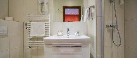 Un baño moderno con lavamanos blanco, toallero, ducha e inodoro.