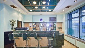 A bar area with a counter, four bar stools, a clock, and a large window. - Hotel Central (Zagreb)