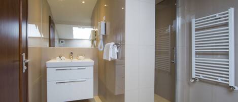 Un baño moderno con tocador, perchero y cabina de ducha de vidrio.