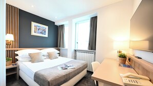 A modern hotel room with a large bed, bedside tables, a desk, and a window with curtains. - Hotel Central (Zagreb)