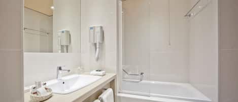 A modern bathroom with two sinks, a large mirror, a shower, and a bathtub.
