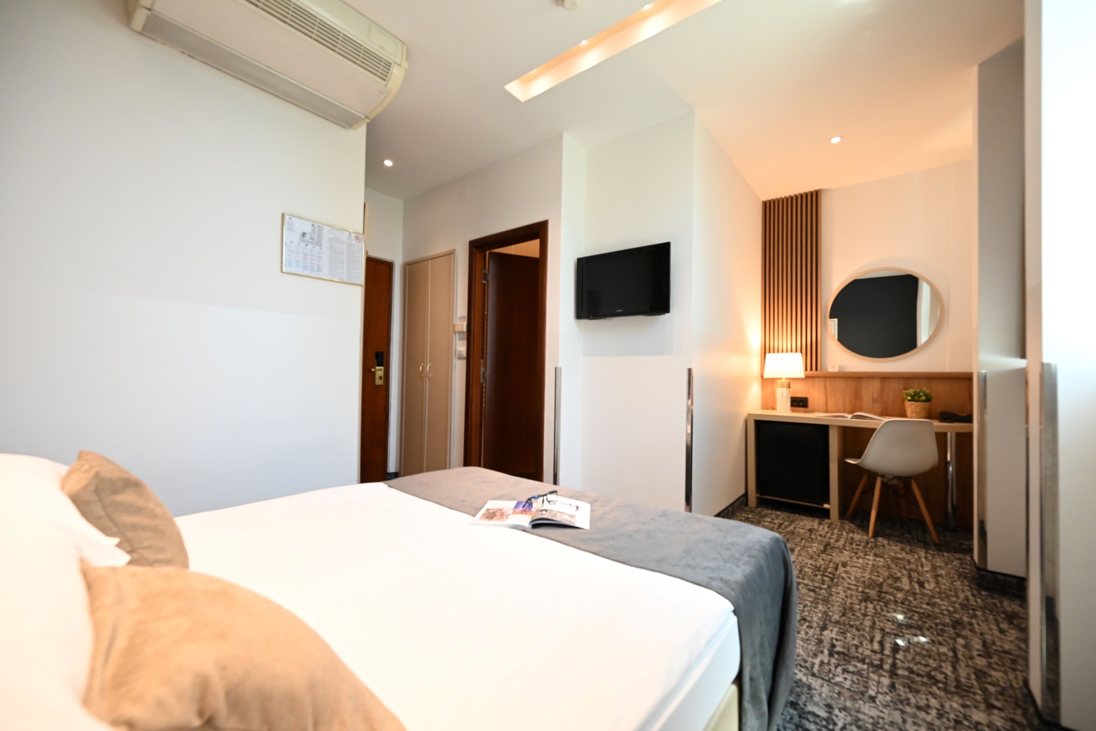 Une chambre d’hôtel équipée d’un lit, d’un bureau, d’une chaise, d’un téléviseur à écran plat et d’un miroir fixé au mur.
